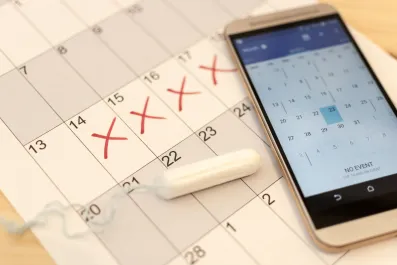 Calendário em papel e no celular para marcar tabelinha de ciclo menstrual