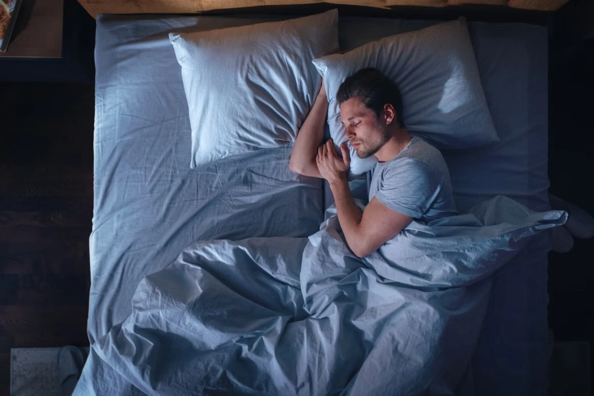 Homem dormindo lateralizado e tranquilo em sua cama