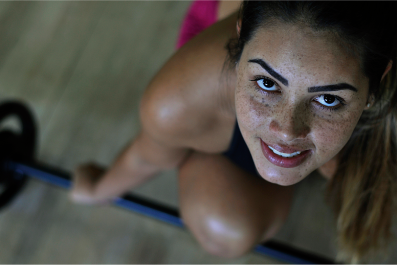 Mulher sorridente pronta para retirar barra olímpica do chão