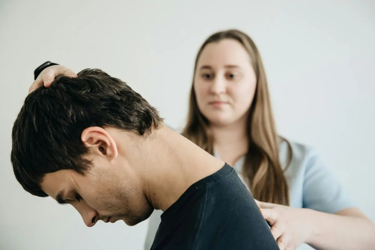 Profissional de saúde realiza um exercício de alongamento no pescoço de um paciente para aliviar a tensão muscular do torcicolo.