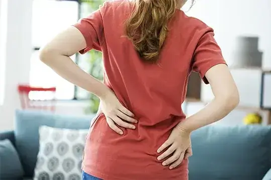 Mulher de costas com as mãos na lombar sentindo dor